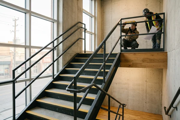 Pan-type steel egress stair with concrete-filled treads and abrasive nosings